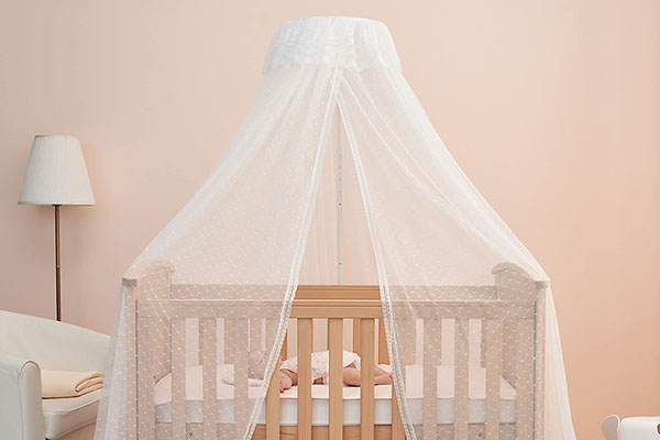 A crib canopy shown with a warning symbol over it for safety reasons