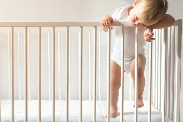 A hand gently wiping down a wooden crib rail with a soft, clean cloth