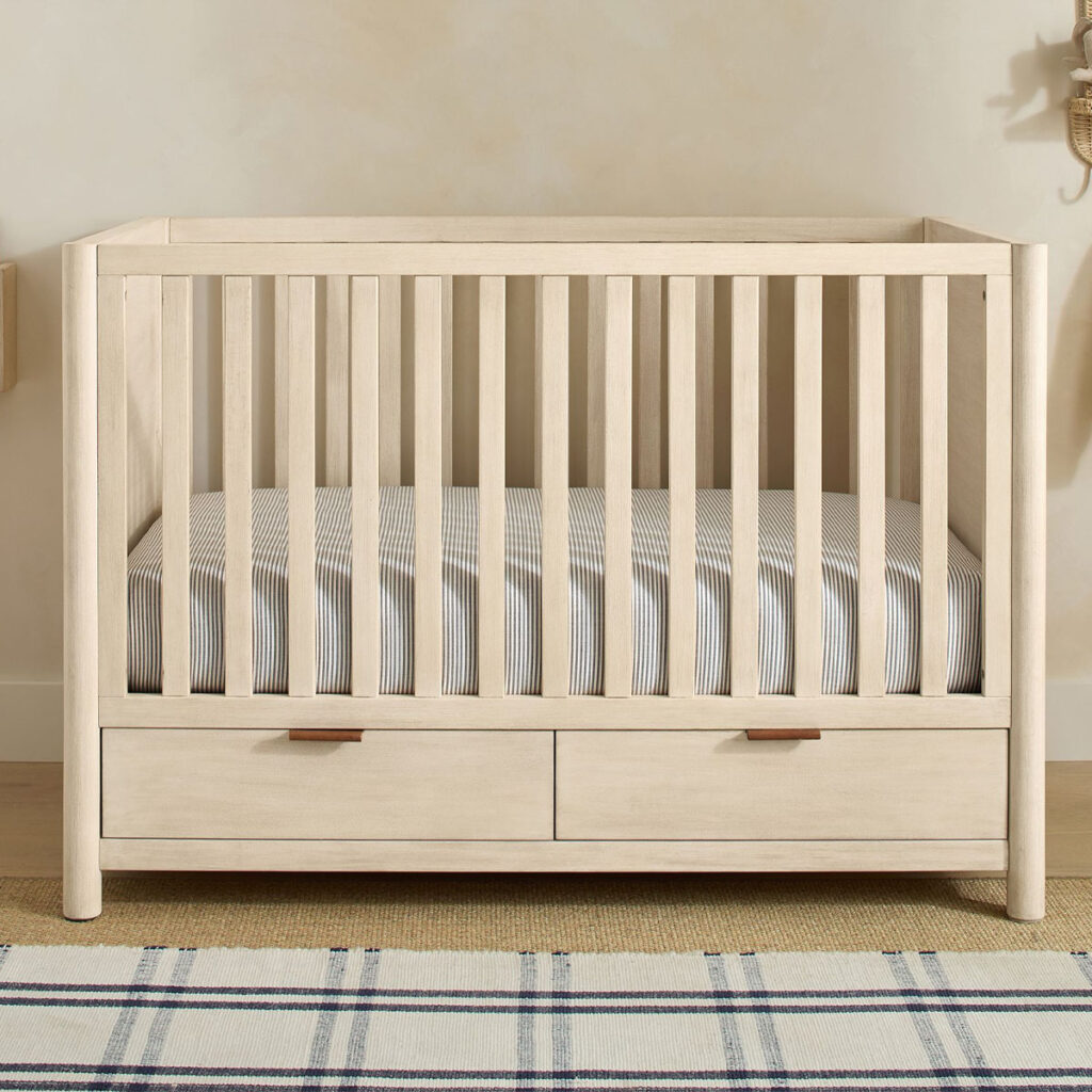 A modern crib with an attached changing table and storage