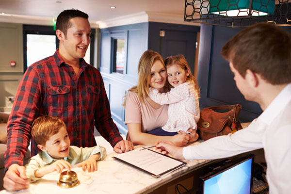 A parent on the phone with a hotel front desk confirming a crib reservation