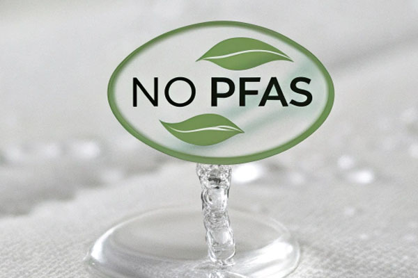 A water droplet bouncing off a certified crib fabric, with a No PFAS symbol