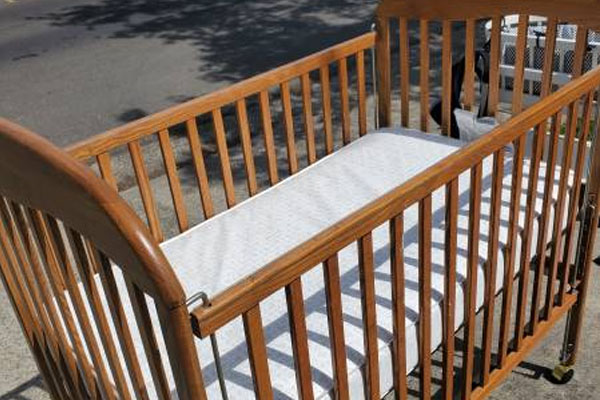 An old, outdated crib with a red X over it to show it's unsafe