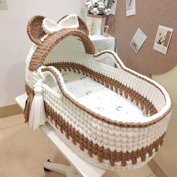 A 4-month-old baby looking almost too big for a Moses basket