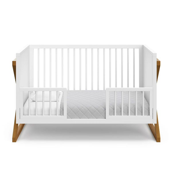 A sidecar crib securely attached to an adult bed, with baby sleeping in their own space