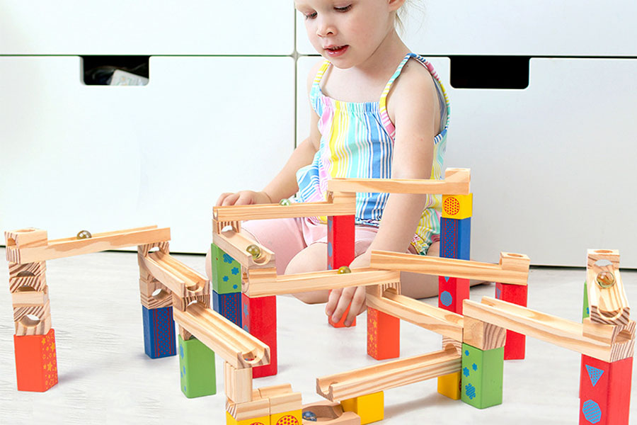 A sturdy, high-quality wooden marble run block side-by-side with a flimsy, cracked plastic one.
